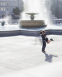 Man lifting woman in front of urban fountain