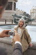 Man with digital camera photographing woman near fountain