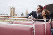 Couple riding double decker bus past Parliament Building in London