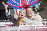 Photo: Wind flipping British flag umbrella over happy couple with map on double decker bus Wind flipping British flag umbrella over happy couple with map on double decker bus