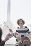 Photo: Man with digital camera taking photograph of happy woman with British flag in front of fountain Man with digital camera taking photograph of happy woman with British flag in front of fountain