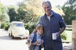 Portrait of smiling grandfather and grandson hugging with coffee mugs in driveway