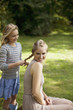 Girl braiding sister?s blonde hair in park