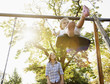 Mother pushing daughter on swing in sunny park