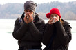 A Young Couple Next To Each Other Blowing Their Noses