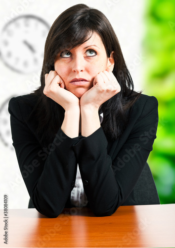 Photo: Bored businesswoman sitting at her desk in her office Bored businesswoman sitting at her desk in her office