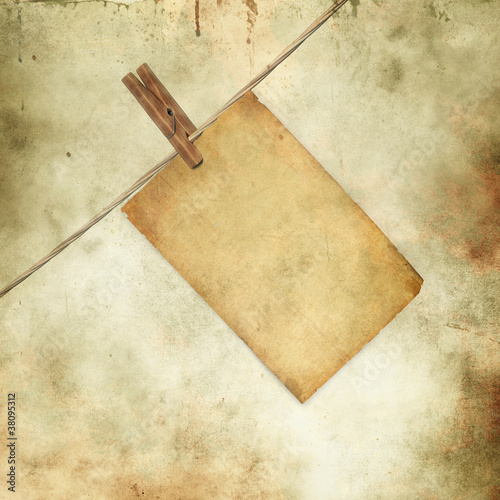 Photo: old blank paper sheet hanging on a rope on grunge background old blank paper sheet hanging on a rope on grunge background