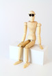 Wooden character sitting and looking at the camera.