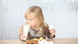 Little blonde drinking milk at the table