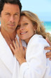 Couple in toweling robes by the ocean