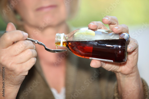 Photo: Woman taking cough medicine Woman taking cough medicine
