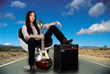 Stylized female guitarist with her amp on the road
