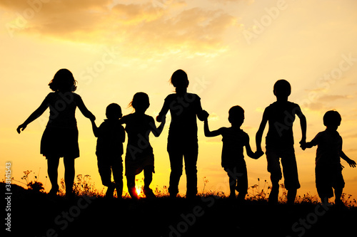 Photo: Silhouette, group of happy children playing on meadow Silhouette, group of happy children playing on meadow