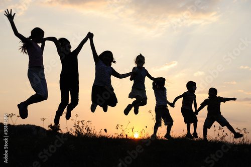 Photo: Silhouette, group of happy children playing on meadow, Silhouette, group of happy children playing on meadow,