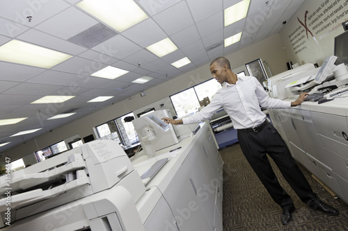 Photo: Man working in printing press between two cash register machine Man working in printing press between two cash register machine