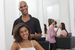 Young woman sitting on chair with hairstylist standing behind