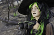 Little witch holding black roses looking away