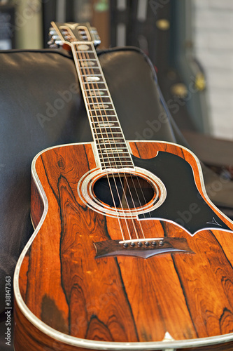Photo: Close-up view of acoustic guitar lying on sofa in music store Close-up view of acoustic guitar lying on sofa in music store
