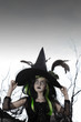 Girl costumed as witch looking up holding her hat
