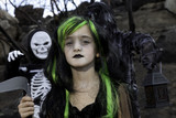 Photo: Portrait of girl dressed up as witch while her friends dressed up in skeleton costume Portrait of girl dressed up as witch while her friends dressed up in skeleton costume