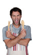 Aggressive cook in apron holding wooden salad servers