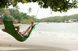 View nice woman lounging in hammock in tropical environment