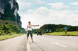 Pretty young woman hitchhiking along a road in tropical location