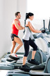 man and woman with elliptical cross trainer at gym man and woman with elliptical cross trainer at gym