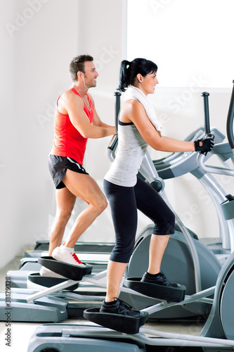 Photo: man and woman with elliptical cross trainer at gym man and woman with elliptical cross trainer at gym