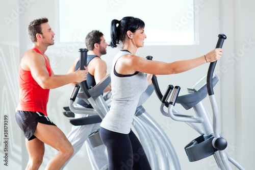 Foto: man and woman with elliptical cross trainer at gym man and woman with elliptical cross trainer at gym