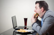 Businessman eating junk food while working