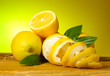 ripe lemons with leaves on wooden table on green background