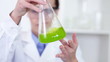 Video: Female scientist mixing erlenmeyer flask with green chemicals Female scientist mixing erlenmeyer flask with green chemicals