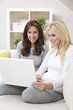 Two Women Using Laptop Computer At Home on Sofa