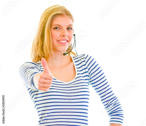 Photo: Smiling beautiful teen girl in headset showing thumbs up Smiling beautiful teen girl in headset showing thumbs up