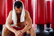 Muscular man sweating, sitting with towel on his shoulders