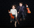 two girls with violins jumping