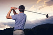 Golfer teeing off at sunset.