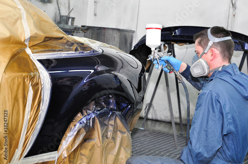 Photo: Worker painting a car. Worker painting a car.