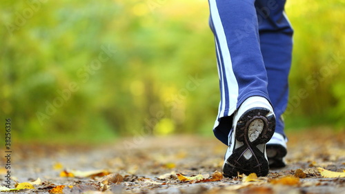 Photo: Woman walking cross country trail in autumn forest Woman walking cross country trail in autumn forest