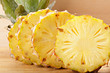Four pineapple slices on cutting board