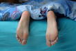 Female feet with callus under the blue blanket Female feet with callus under the blue blanket