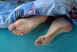 Female feet with callus under the blue blanket Female feet with callus under the blue blanket