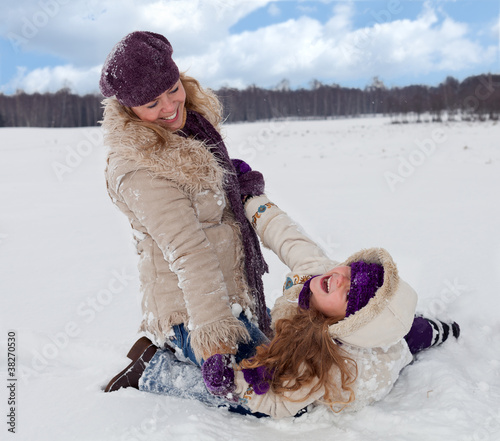 Photo: Woman and little girl having fun in the snow Woman and little girl having fun in the snow