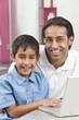 Asian Indian Father & Son Using Laptop Computer at Home