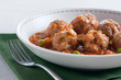 Stewed meatballs with peas, tomato and onion