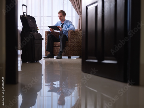 Photo: Businessman using digital tablet pc in hotel room Businessman using digital tablet pc in hotel room