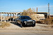 Rolls Royce parked on roadside in front of abandoned house