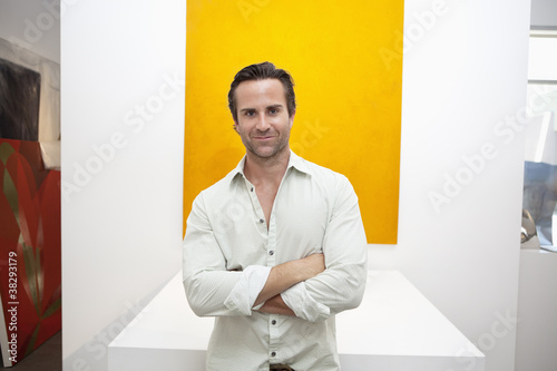 Photo: Half-length portrait of smiling young man in front of yellow painting Half-length portrait of smiling young man in front of yellow painting