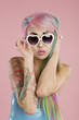 Young woman posing wearing sunglasses over pink background
